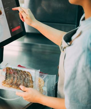 Person using digital POS system in a restaurant for cashless food payment.